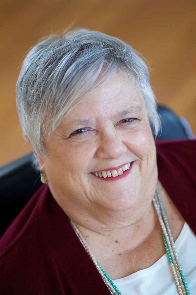 an elderly woman with short grey hair and a red shirt